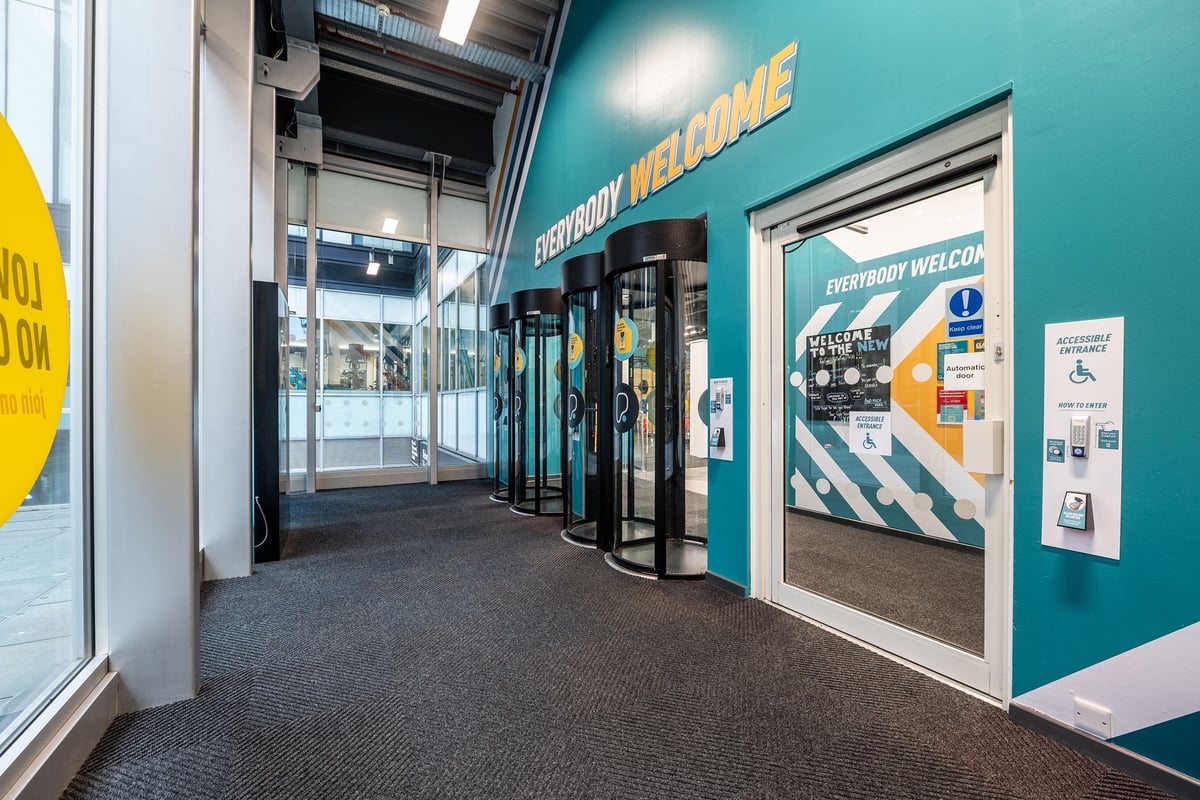 PureGym Manchester Spinningfields: Entrance lobby with security gates, welcome signage and directory.