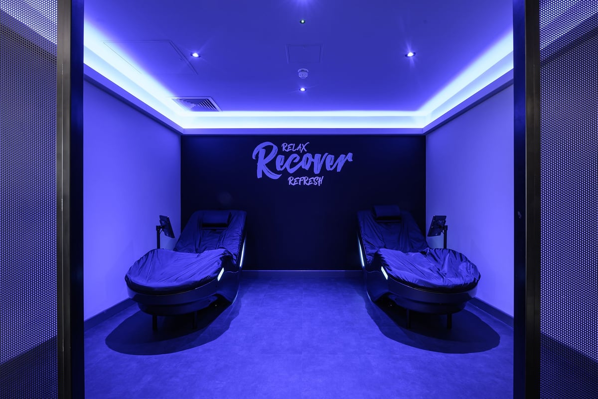 PureGym London Fulham: Compact relaxation area with reclining chairs and blue mood lighting.