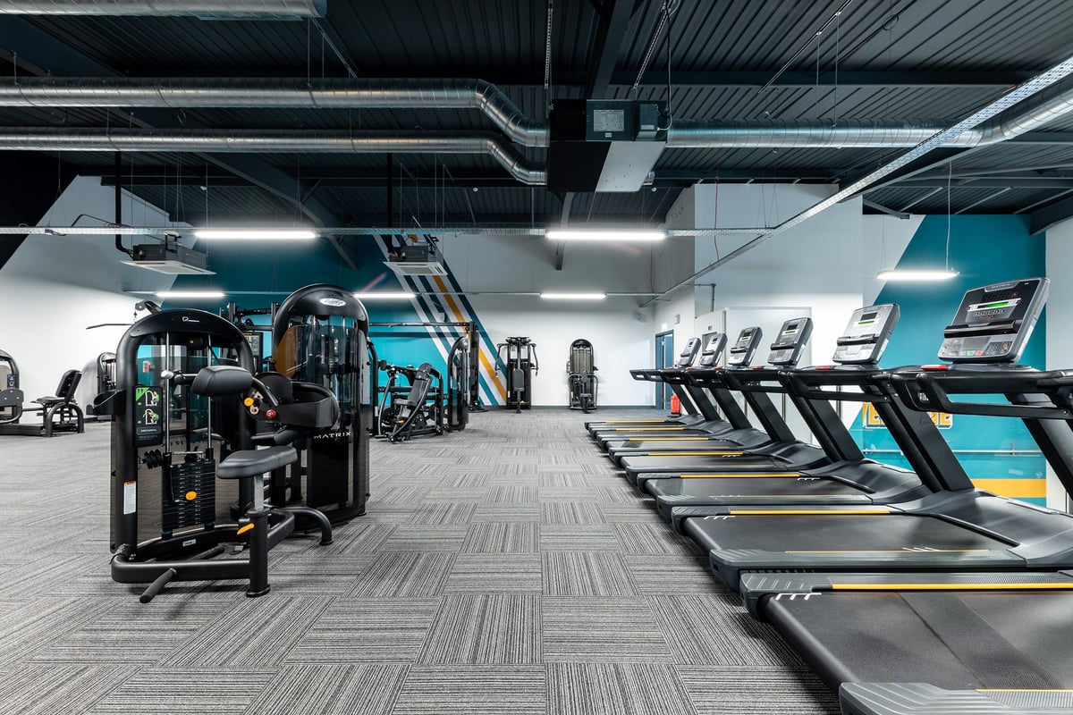 PureGym Sevenoaks: Rows of futuristic-looking treadmills, weight machines in vibrant teal and grey colour scheme.
