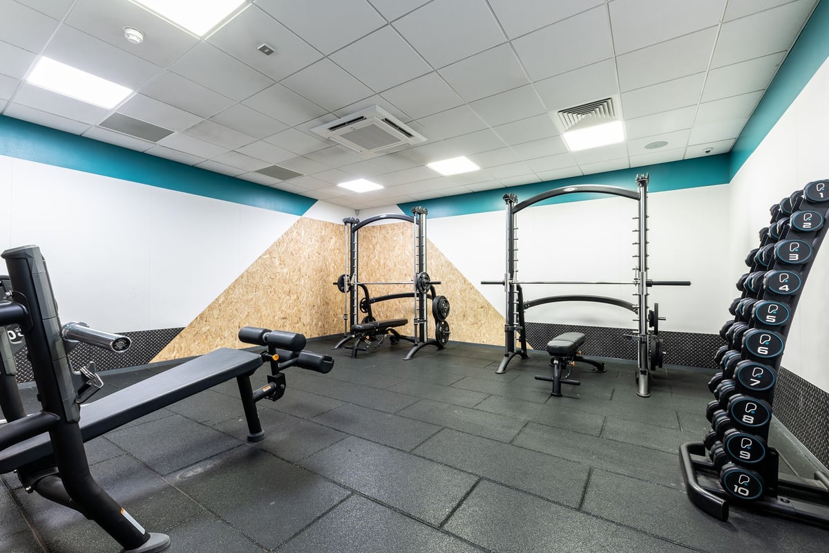 PureGym Cambridge Leisure Park: Strength racks, benches, rubberized flooring, dumbbell racks in a teal and white gym studio.