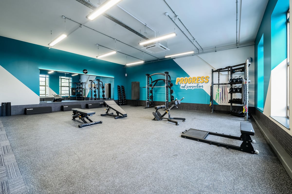 PureGym London Wimbledon: Strength training area with racks, benches, free weights, and padded flooring.