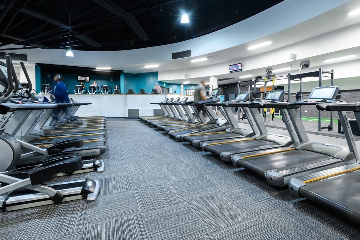 PureGym Northampton Central: Rows of treadmills, cross-trainers, and stationary bikes in a dimly lit gym interior.