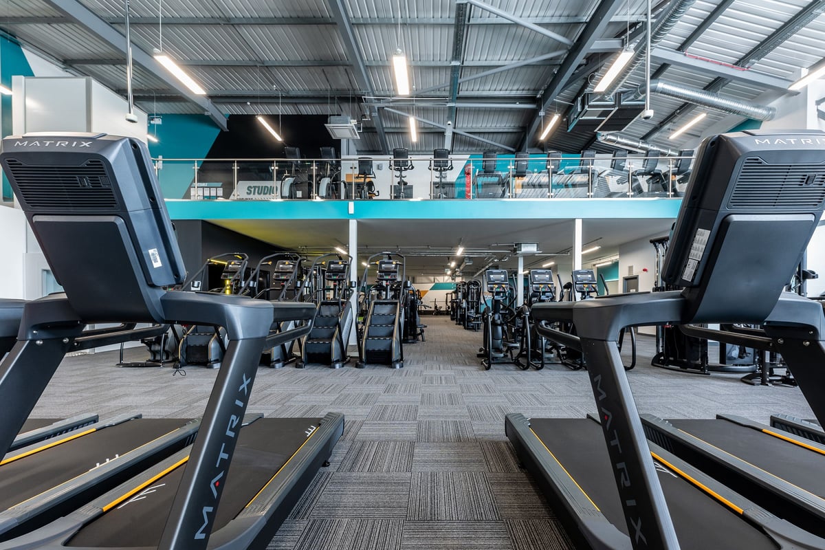 PureGym Tamworth: Rows of treadmills, ellipticals, and stationary bikes with overhead mirrored walls.