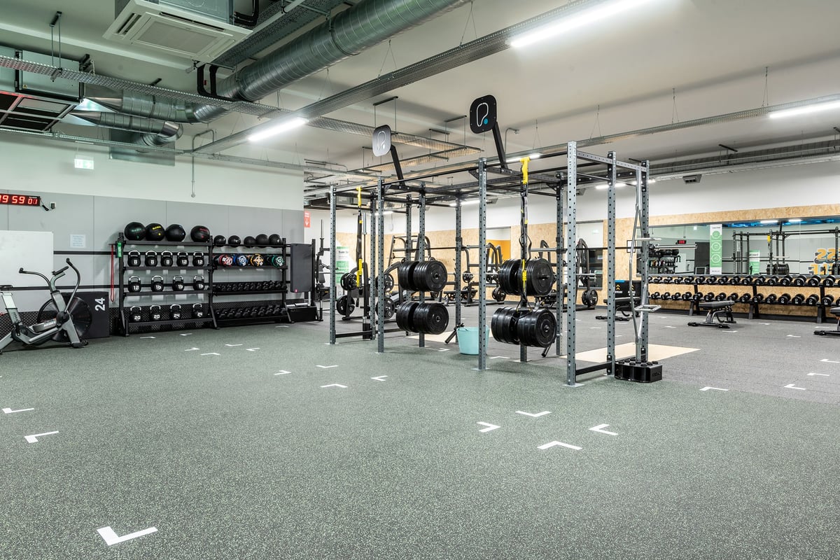PureGym Witney: Squat racks, weight plates, benches, rubberized flooring in a gym studio.