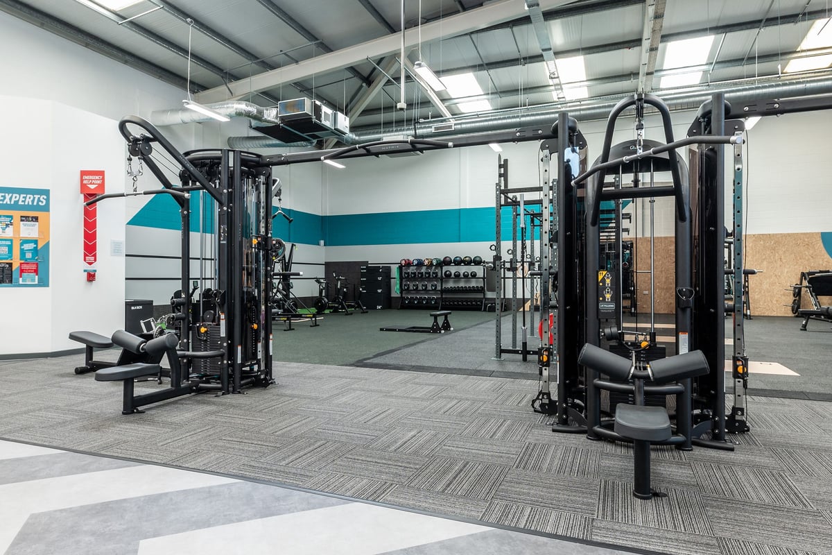 PureGym Dumfries: Functional training rigs, weight racks, benches, and rubberized flooring in a gym space.