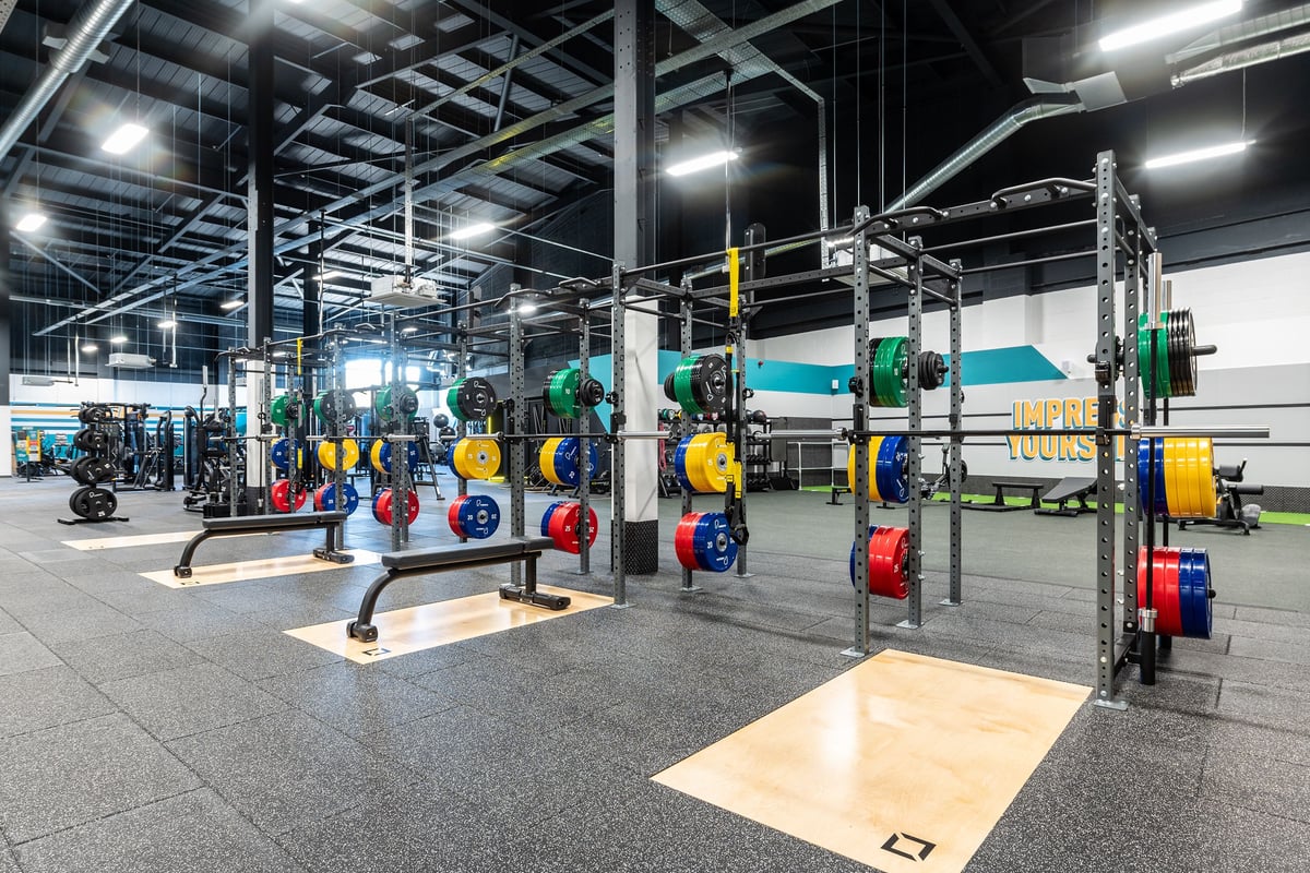 PureGym Stockton-on-tees Teesside Park: Racks with weights, benches, rubberized floors in a brightly lit gym facility.