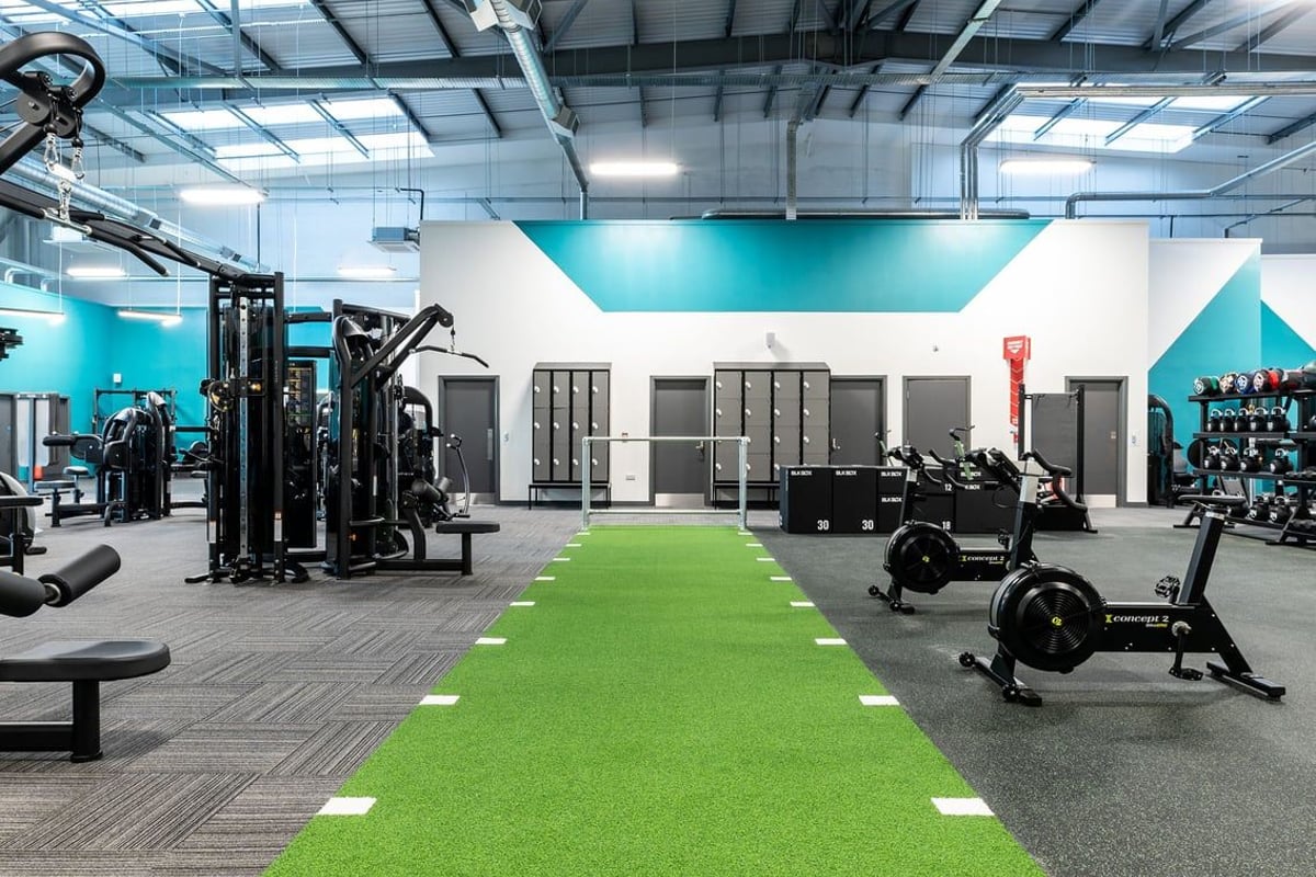 PureGym Kirkby: Free weights, strength machines, turf area, and mirrored walls in a modern gym setup.