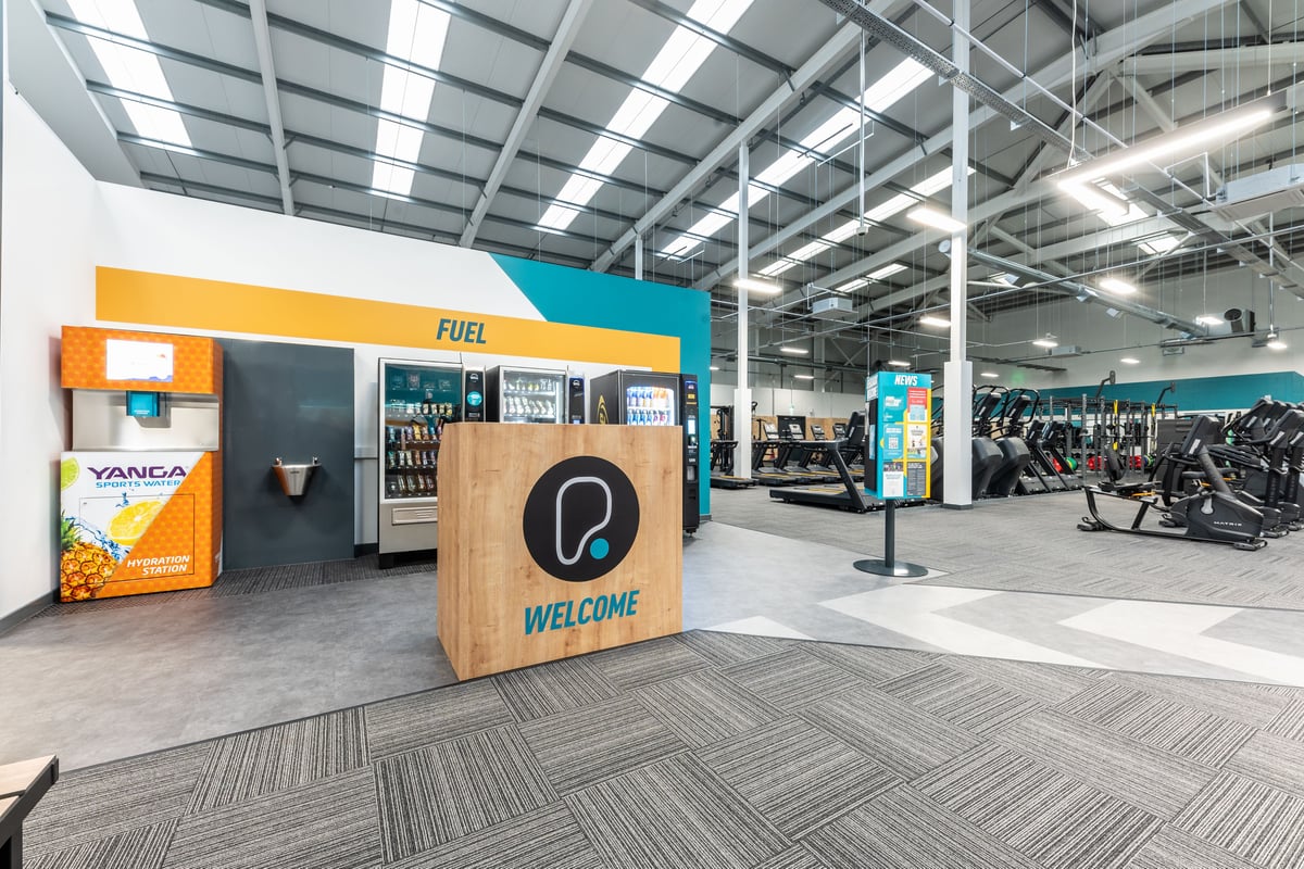 PureGym Port Talbot: Fuel bar, cycles, and rubberized flooring in a bright gym setting.