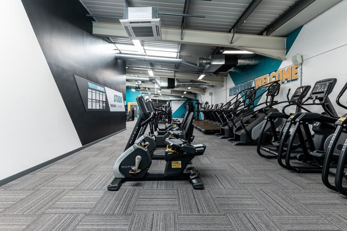 PureGym Gloucester Retail Park: Rows of cardio machines, weight benches, and strength equipment in a modern gym studio.