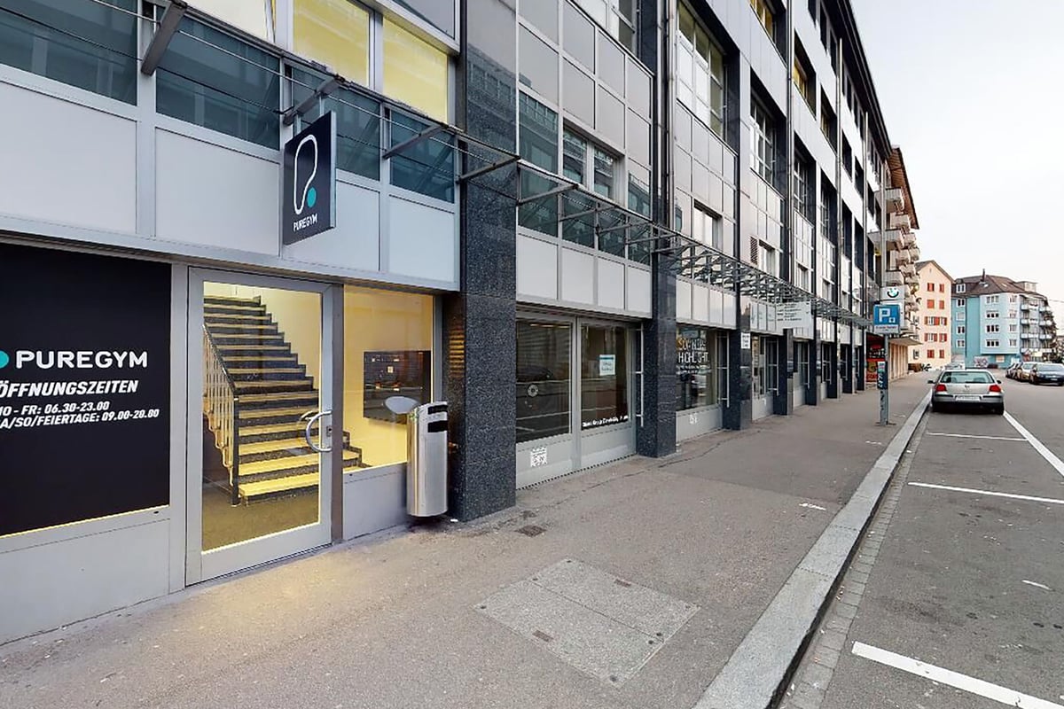 PureGym Zürich Lochergut: Extérieur du centre de conditionnement physique avec escalier jaune, signalisation sur la devanture indiquant « PUREGYM ».