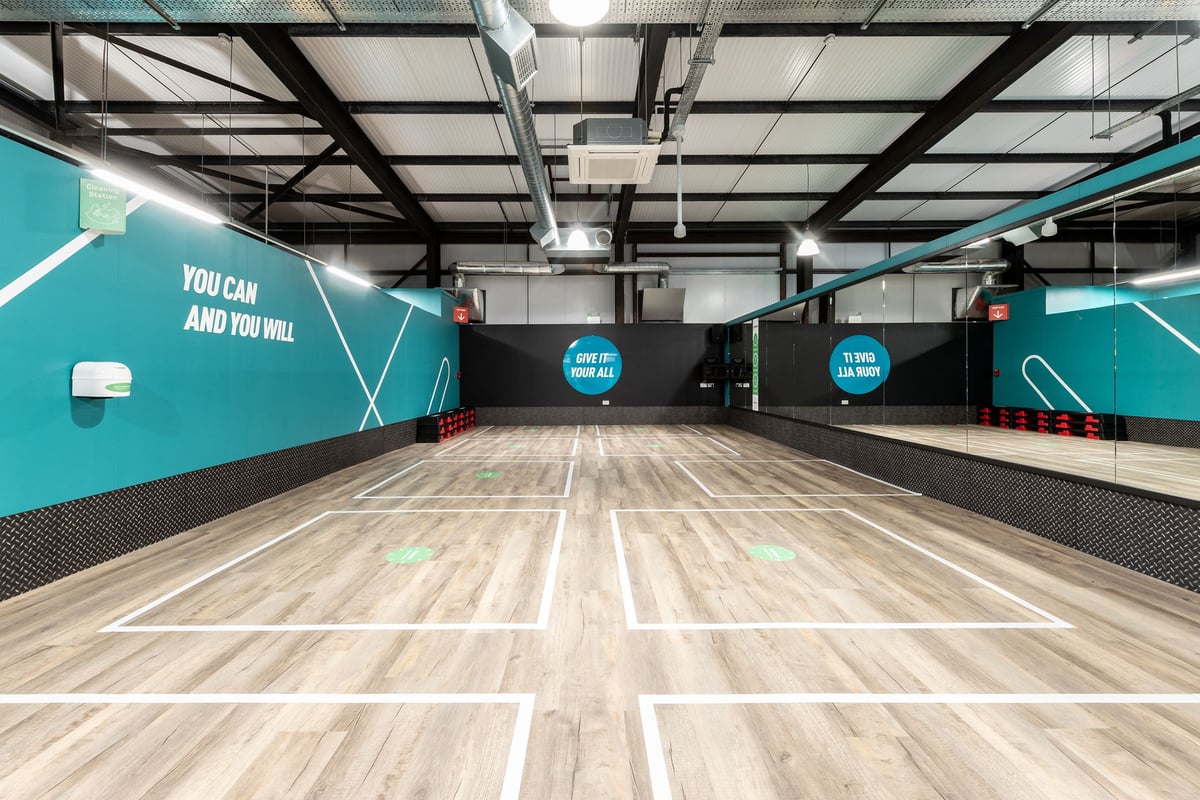 PureGym Kirkcaldy: Teal-accented functional training area with rubberized flooring, motivational messaging on walls.