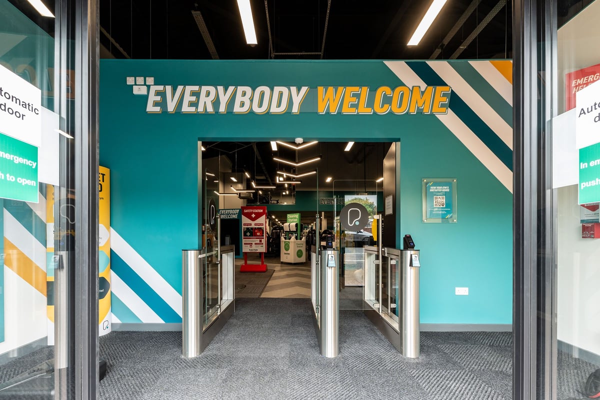 PureGym Redditch Ringway: Entrance area with turnstiles, posters displaying "everybody welcome" message.