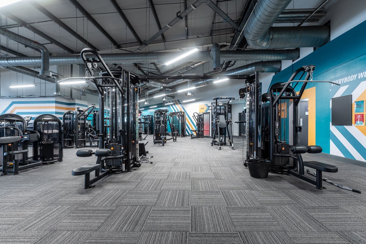 PureGym Loughborough: Free weight machines, benches, rubberized flooring in a spacious gym interior.