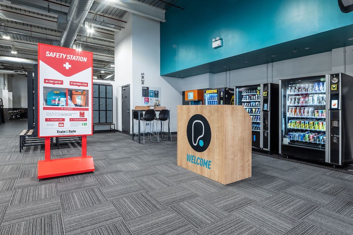 Reception area with vending machines, a welcome desk, and a safety station sign