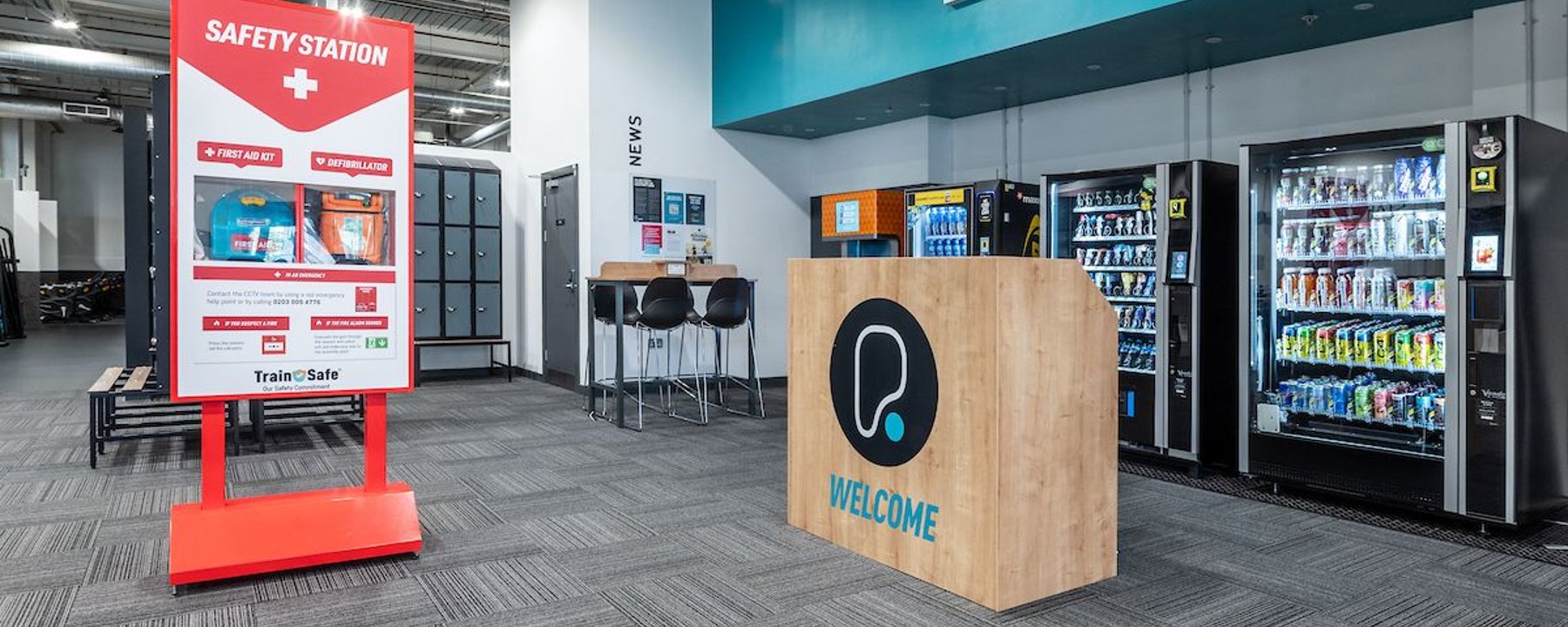 Reception area with vending machines, a welcome desk, and a safety station sign
