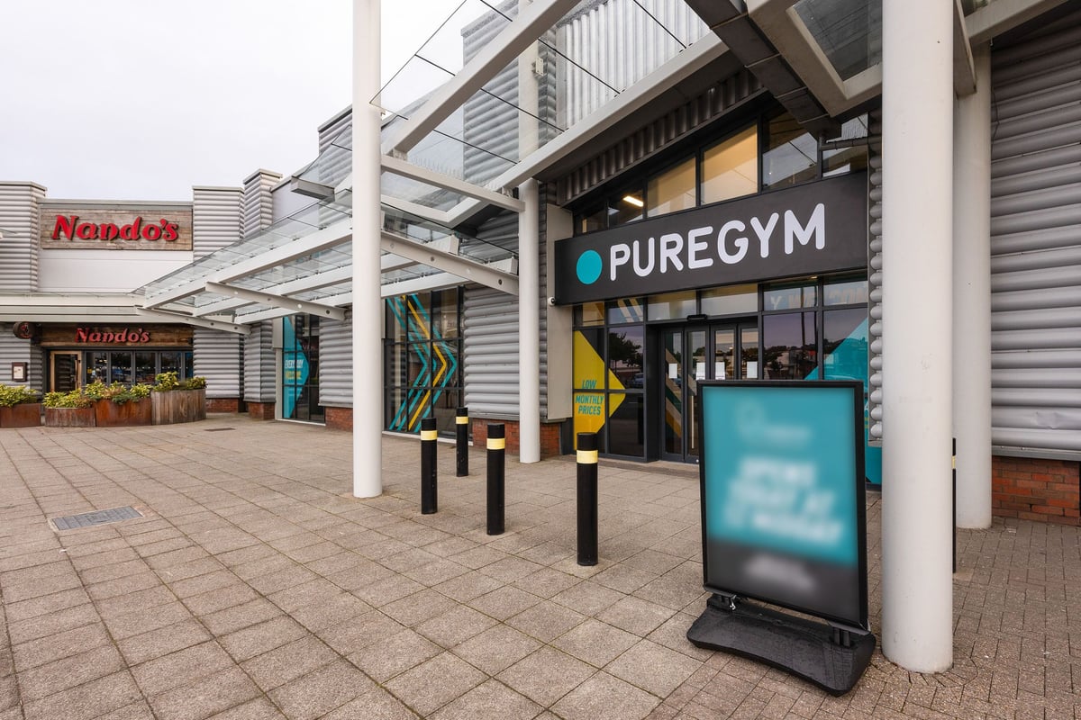 PureGym Falkirk: Gym storefront with logos, signage, and outdoor seating area.