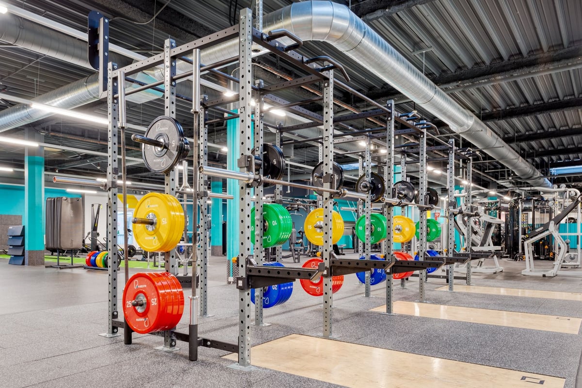 PureGym Bachenbülach : des supports de rangement colorés présentent des plaques de musculation pour la