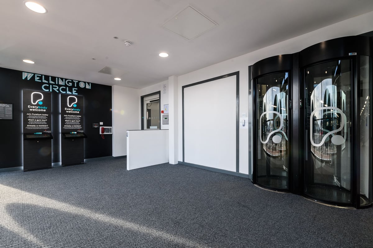 PureGym Aberdeen Wellington Circle: Lift entrance area with weightlifting plates artwork on glass doors.