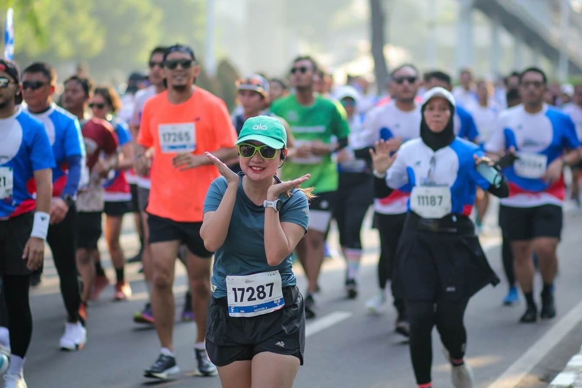 Child in green cap and sunglasses running in outdoor race with other participants