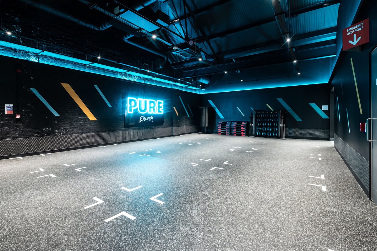 PureGym Puregym Crayford: Fitness studio with neon "PURE" branding and directional floor markings.