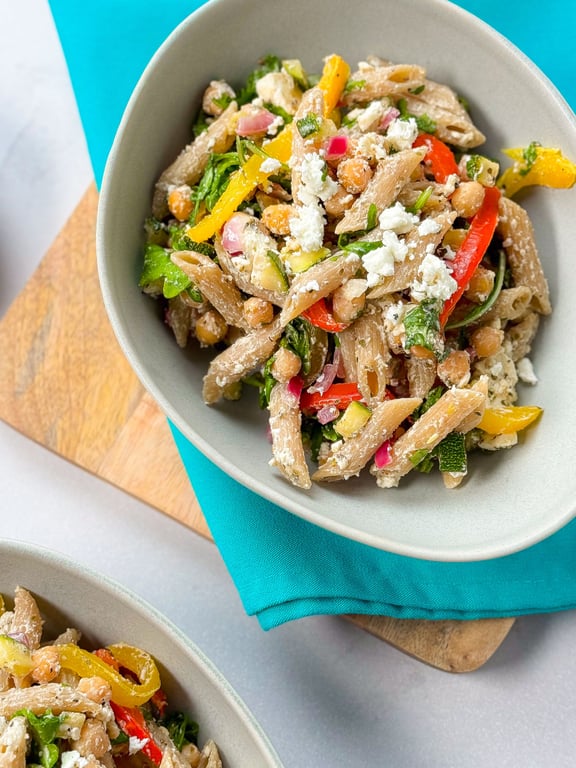Whole wheat penne pasta salad with chickpeas, feta, and mixed vegetables in bowls