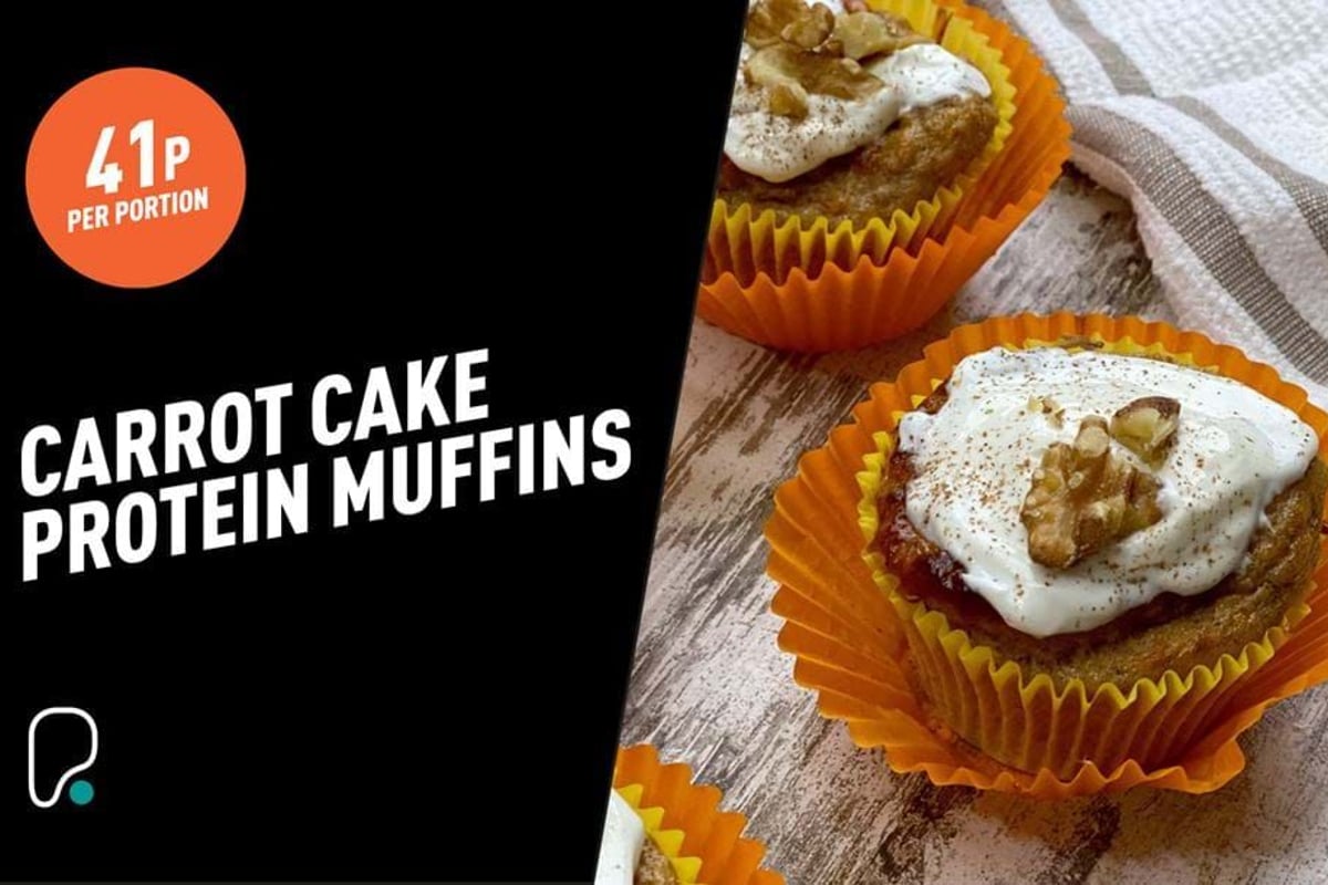 Carrot cake protein muffins with cream cheese frosting and walnut halves in orange cases