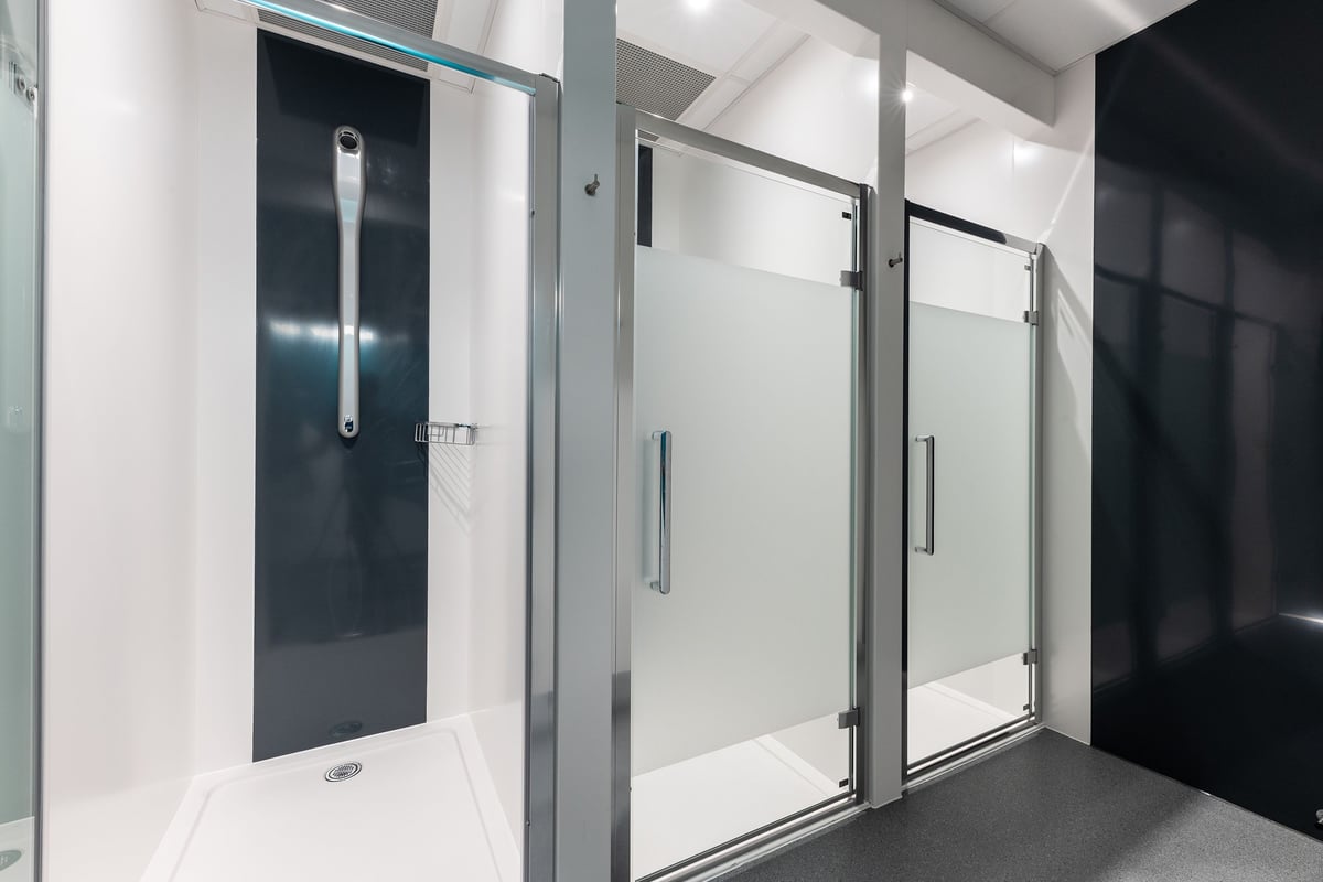 PureGym Shrewsbury Meole Brace: Shower stalls with glass doors, tiled floors, stainless steel handles.