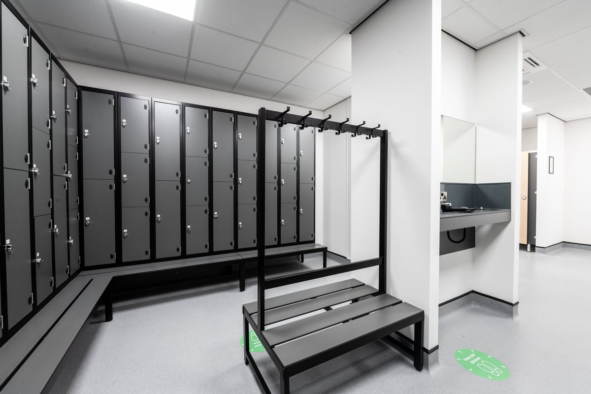 PureGym Plymouth Marsh Mills: Rows of lockers, benches, and shower facilities in a gym's changing room.