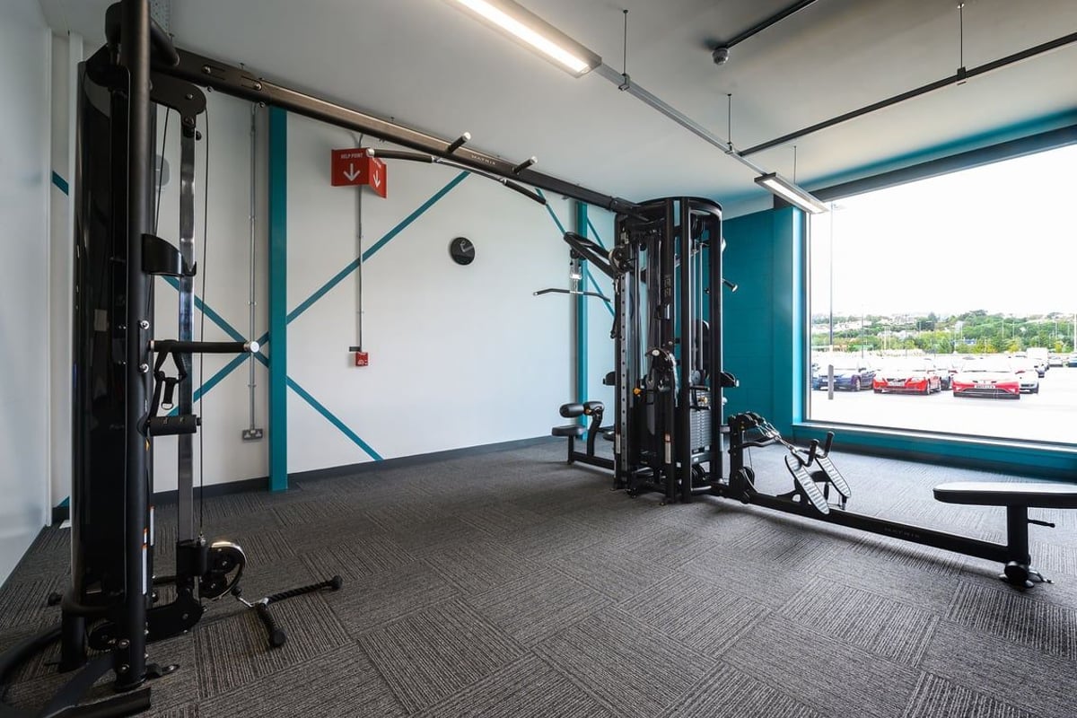 PureGym Barnstaple: Weightlifting racks, resistance machines, benches, and rubberised flooring in a brightly-lit gym studio.