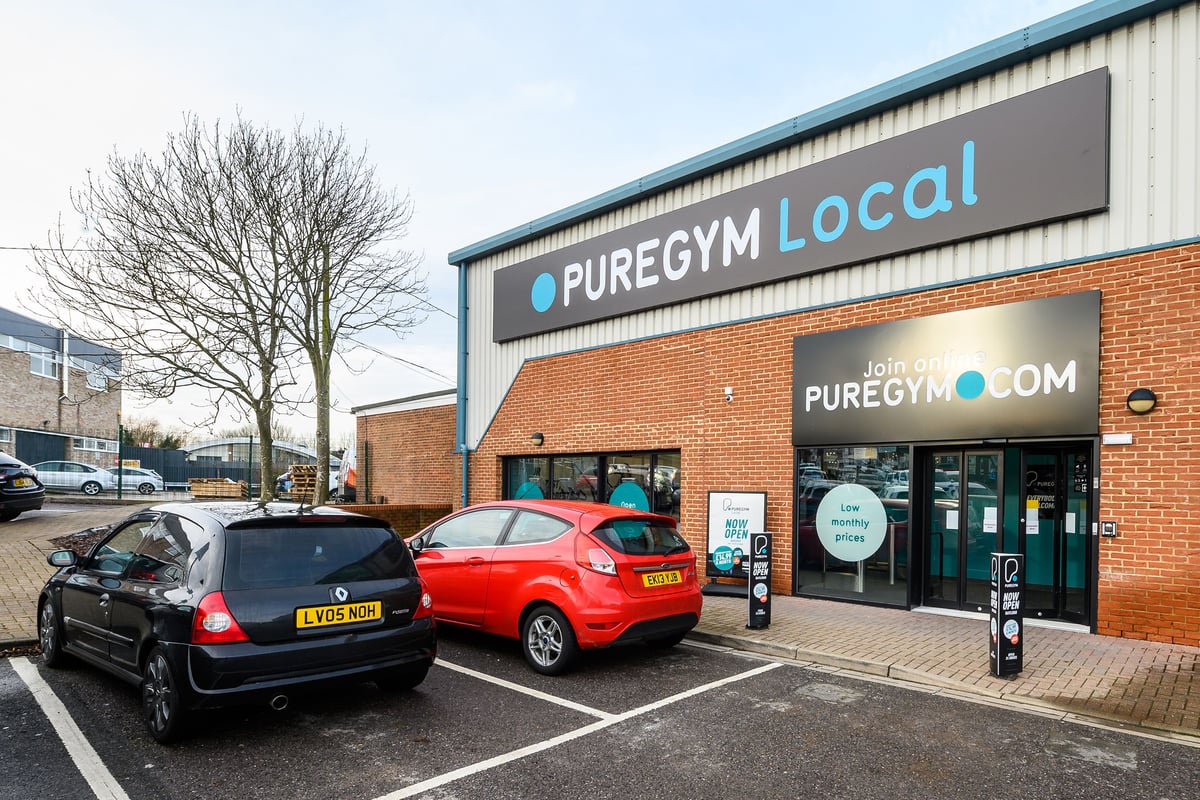 PureGym Rayleigh: Exterior of a local gym with signage, parked cars, and some trees.