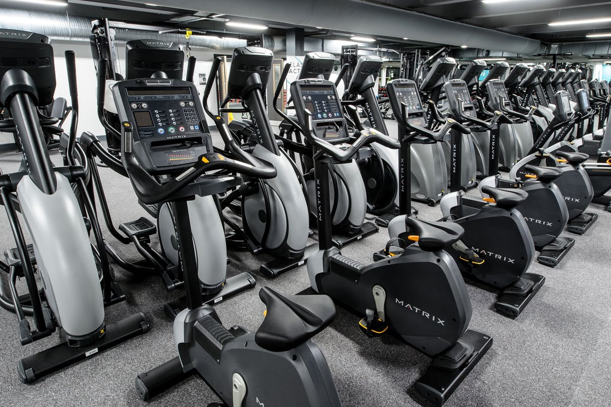 PureGym London Wembley: Rows of elliptical trainers, treadmills, and exercise bikes in a gym setting.