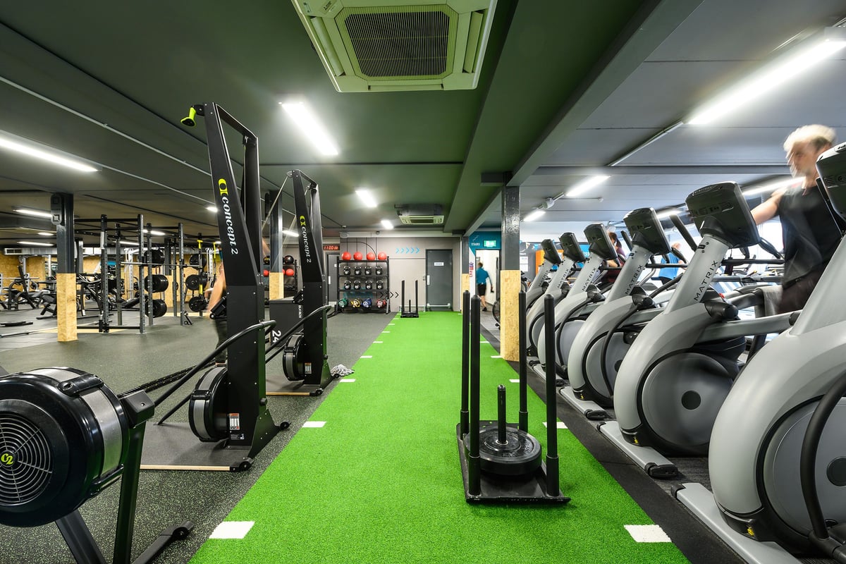 PureGym Reading Caversham Road: Rows of cardio machines, weight racks, benches, mirrors in a green and grey fitness studio.