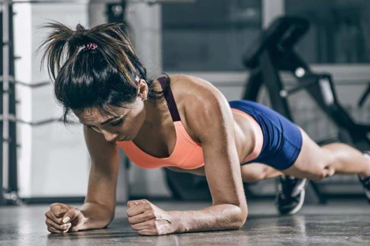 Femme en tenue de sport faisant la planche au sol de la salle de sport