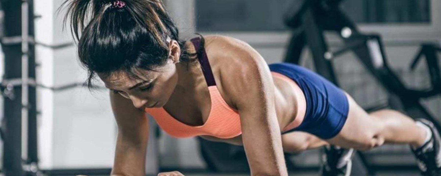 Femme en tenue de sport faisant la planche au sol de la salle de sport