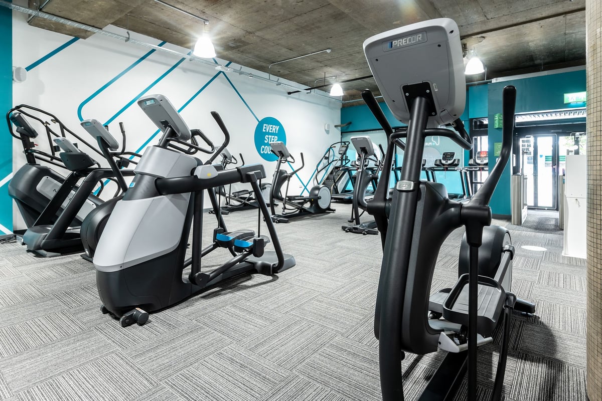 PureGym London Leytonstone: Rows of elliptical trainers, treadmills, and exercise bikes in a gym with teal accents.