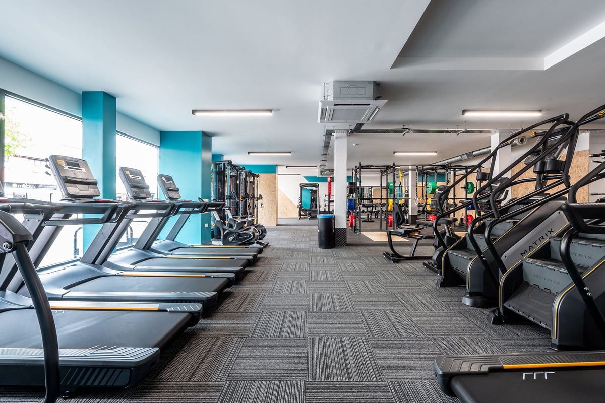 PureGym London Welling: Rows of treadmills, ellipticals, weight machines in a modern gym with teal accents.