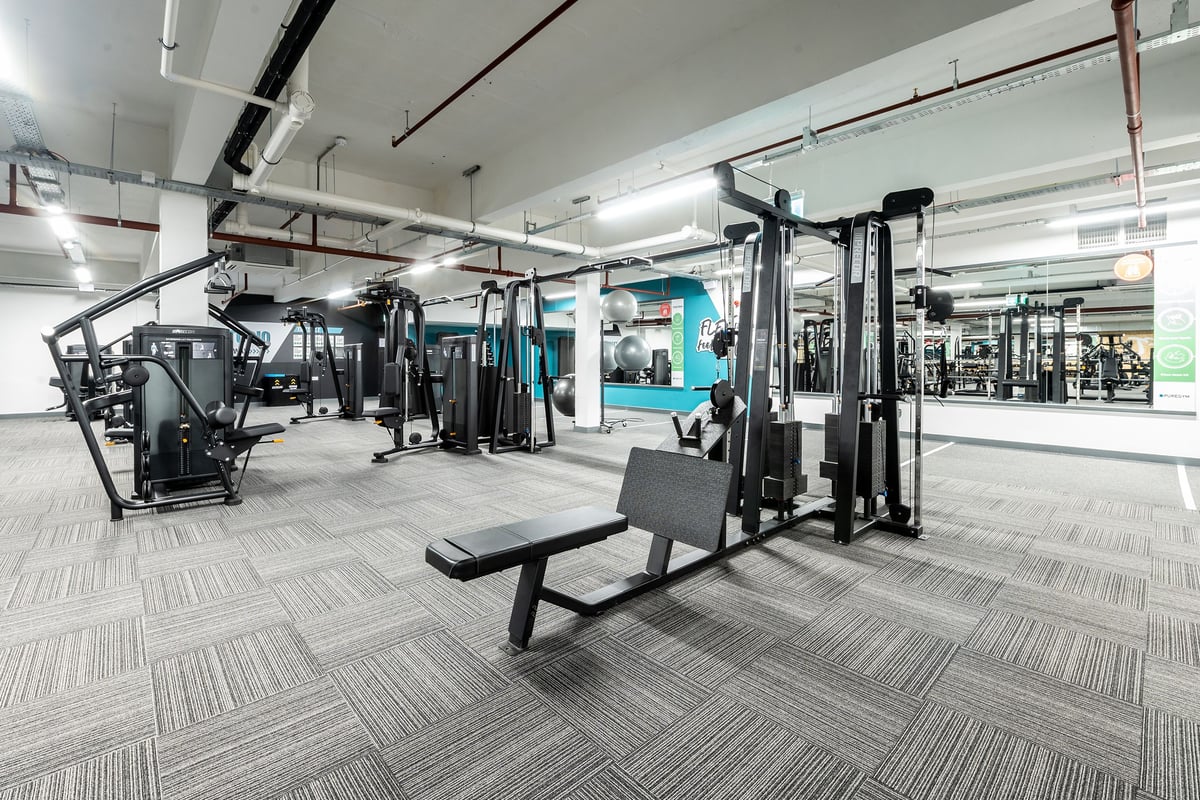 PureGym Gravesend: Resistance training machines, weighted stations, benches, rubberised flooring in a spacious gym area.