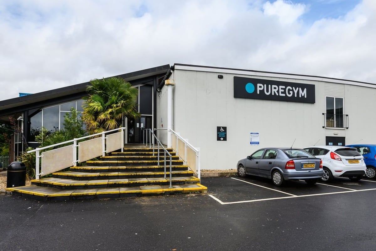 PureGym Burnham: Gym exterior with palm trees, stairs, parking spaces.