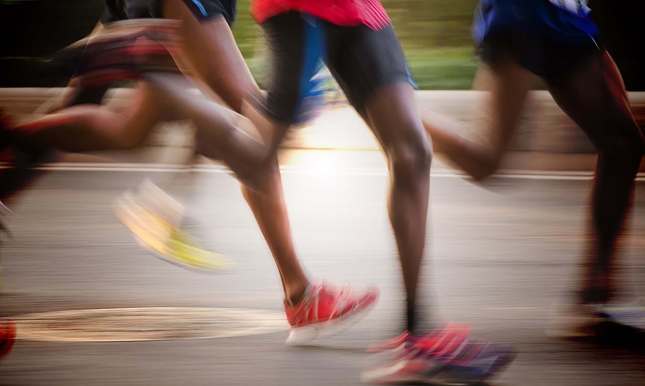blurred legs of runners in motion on a road during a race