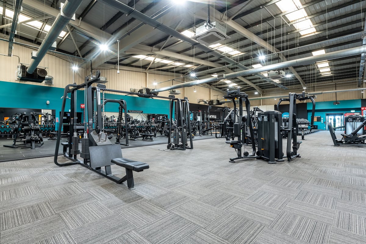 PureGym Weston-super-mare: Strength training equipment like cable machines, squat racks and benches on rubberized flooring.