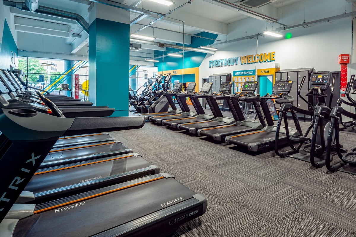 PureGym Leicester St Georges Way: Rows of treadmills, turquoise accents, and wall graphics in a bright fitness studio.