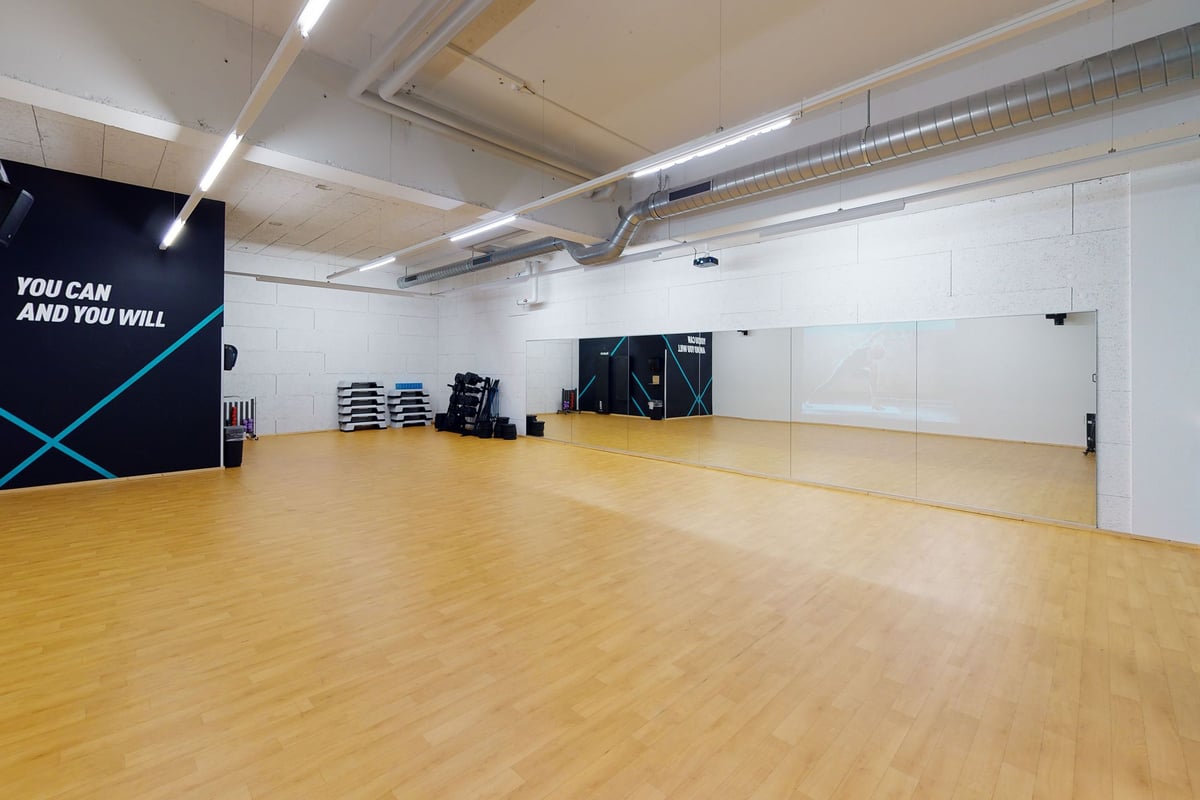 PureGym Pfäffikon: Grosser offener Fitnessbereich mit Holzboden und Spiegelwand.
