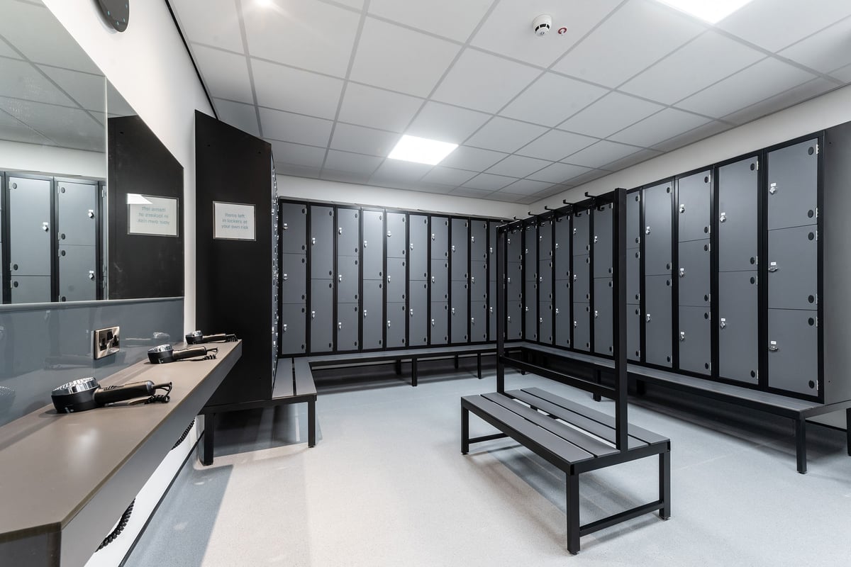 PureGym Tyldesley: Lockers, benches, and a counter in a changing room area.