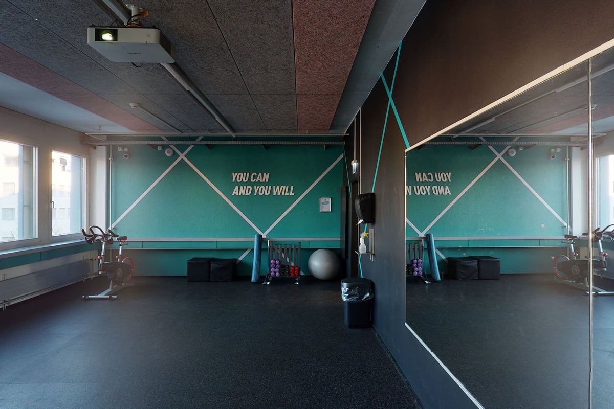 PureGym Wetzikon: Fitnessstudio mit verspiegelten Wänden, Gymnastikbällen, Hanteln und Motivationssätzen.