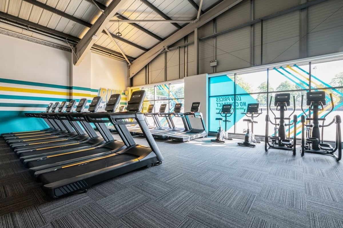 PureGym Leeds Bramley: Rows of treadmills, ellipticals, and weight machines in a bright gym interior.