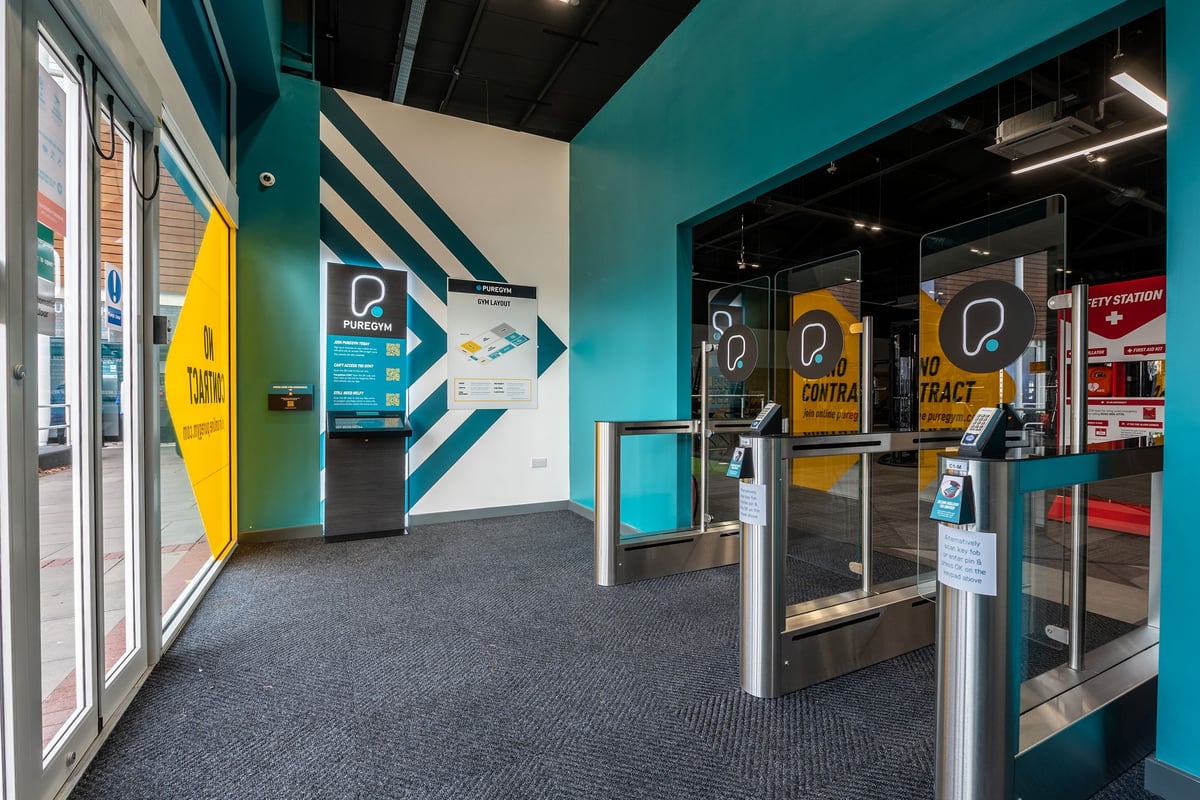 PureGym Walsall Crown Wharf: Signage, queueing barriers, teal walls in what appears to be a gym reception area.