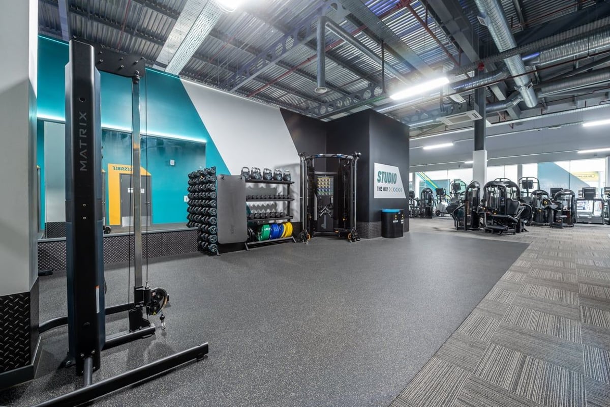 PureGym Peterborough Serpentine Green Shopping Centre: Gym studio with weight racks, cardio machines, and rubber flooring.