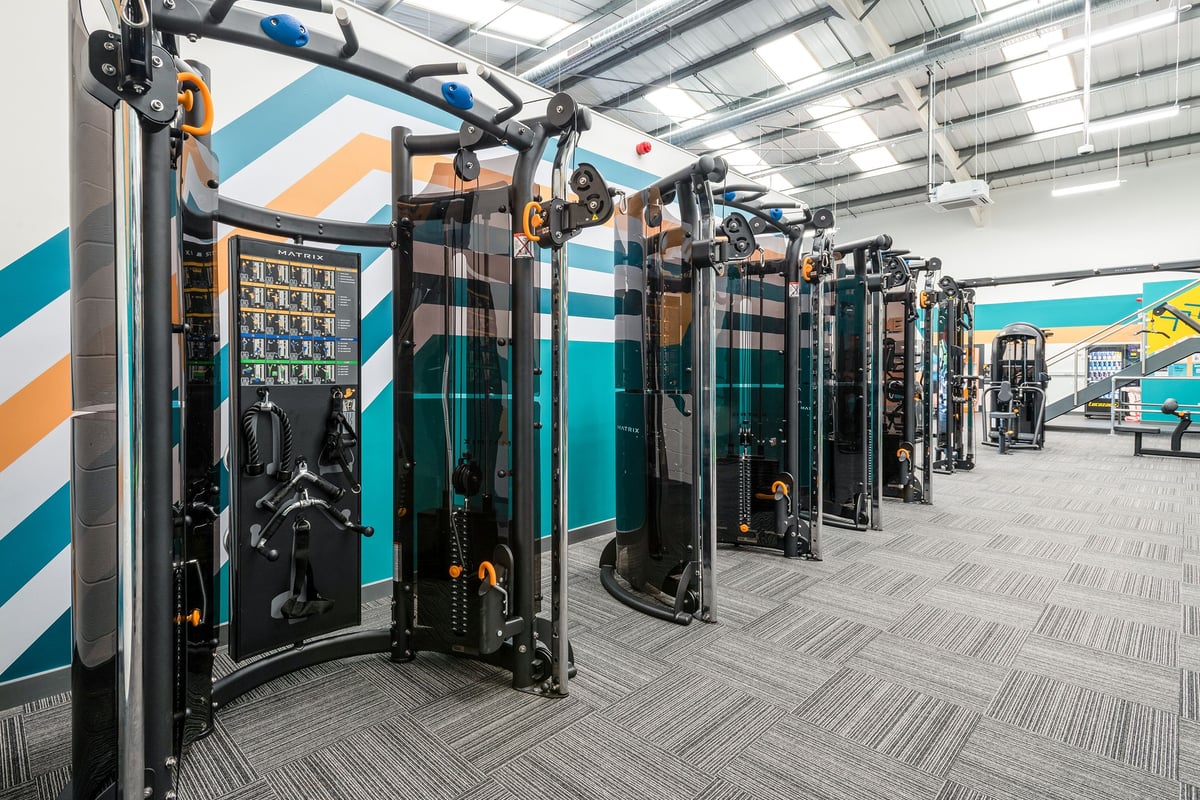 PureGym Cannock Orbital Retail Park: Rows of cable cross-over machines with weight stacks in a gymnasium setting.