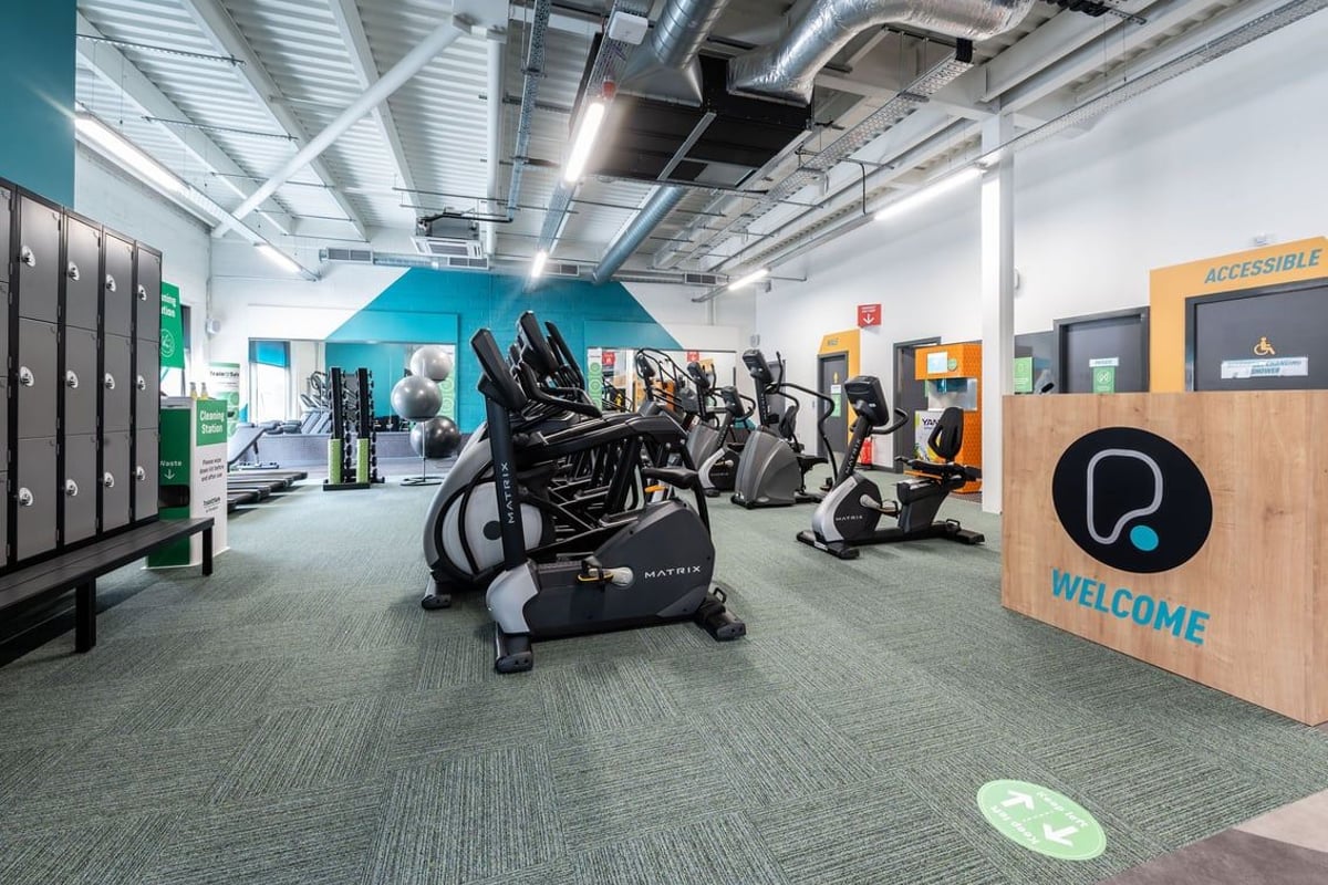 PureGym Aldershot Westgate Retail Park: Rows of stationary bikes, ellipticals, racks of dumbbells in a bright gym interior.