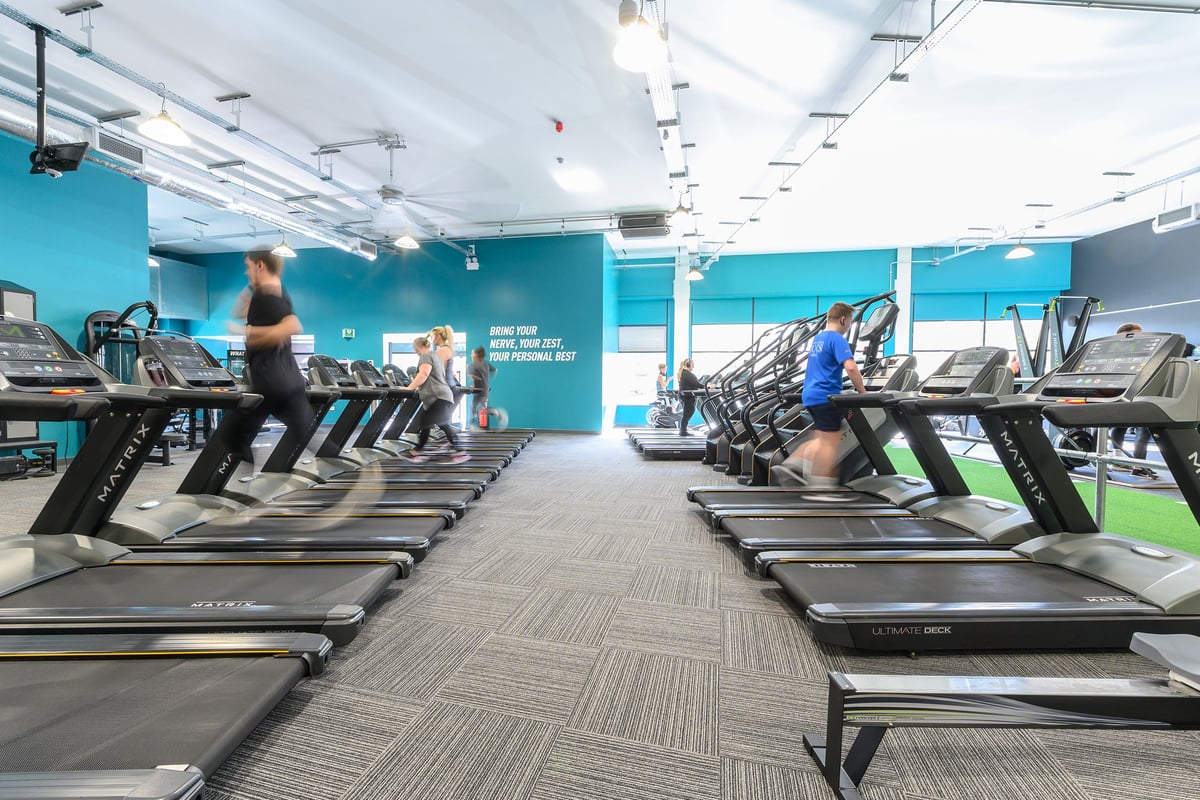 PureGym Bath Spring Wharf: Rows of treadmills inside a gym with teal walls and mirrored panels.